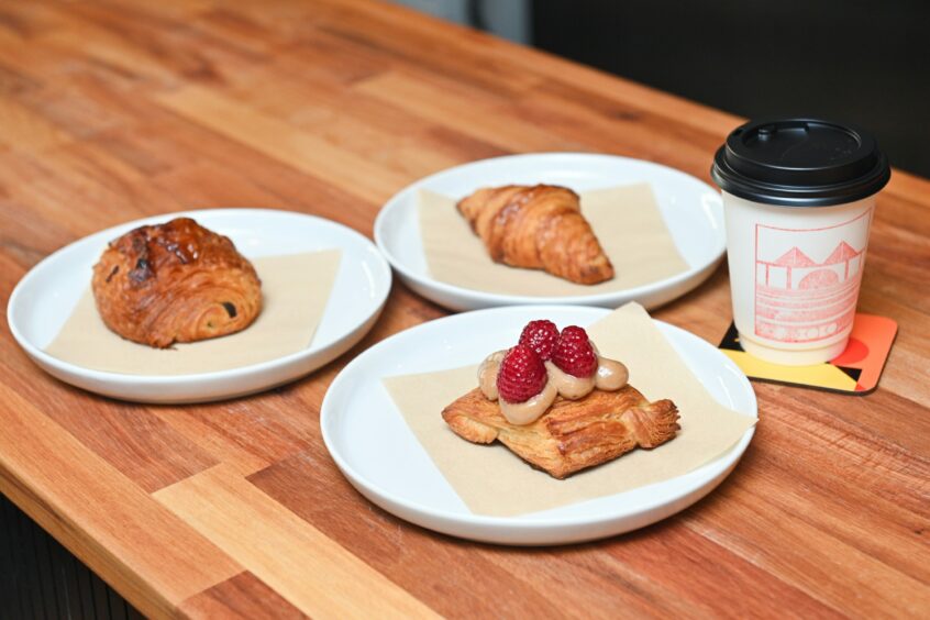 Three pretty pastries and a cream takeaway coffee cup with red design available from XOKO. 