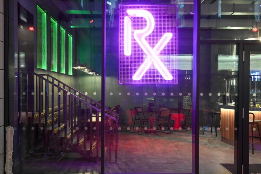 The glass exterior of Resident X with a purple neon sign reading 'RX'