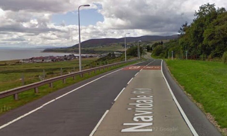 The single carriageway, two lane A9 road at Navidale, curves to the right, then back to the left. The sea is on the left and the Sutherland hills rise in the distance. 