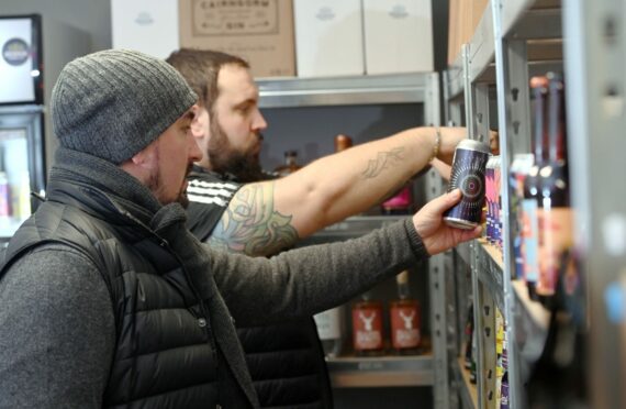 Two men looking through Scottish beers in a bottleshop run by Devenick Drinks Co.
