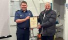 Tom Rennie receiving his long service award from senior coastal operations officer Colin Wood. Image: HM Coastguard.