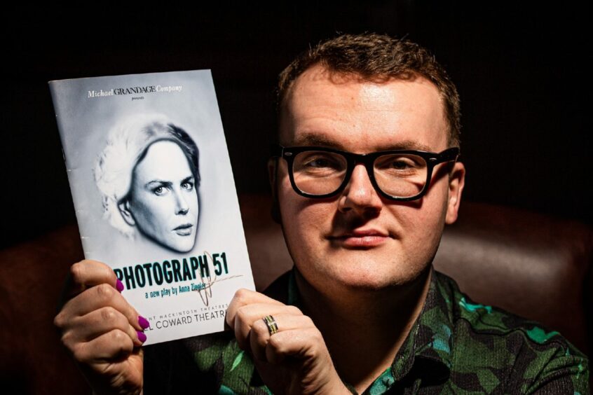 James Davidson looks directly into the camera, holding a programme for London play Photograph 51 which featured his Mastermind subject Nicole Kidman. 