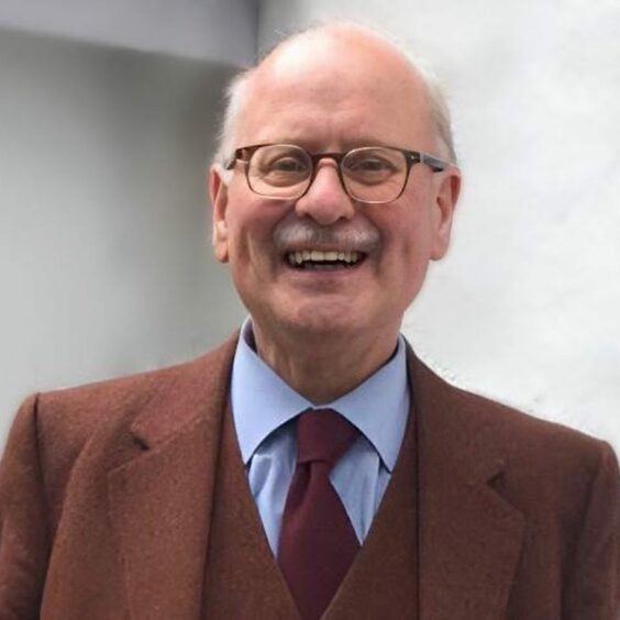 Dr Roddy Macleod pictured smiling, wearing his trademark tweed suit.