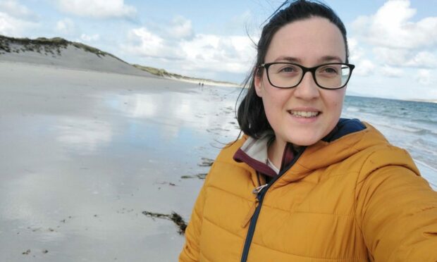 A woman takes a selfie on a beach.