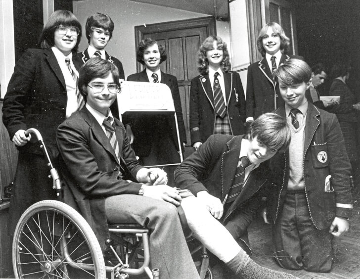 1980 - Despite a broken arm and leg, Spean Bridge lad John Godfrey travelled to the Mitchell Hall, Aberdeen, for a debating contest. Stuart Hepburn, Peterhead, signs his cast, while other competitors wait their turn.