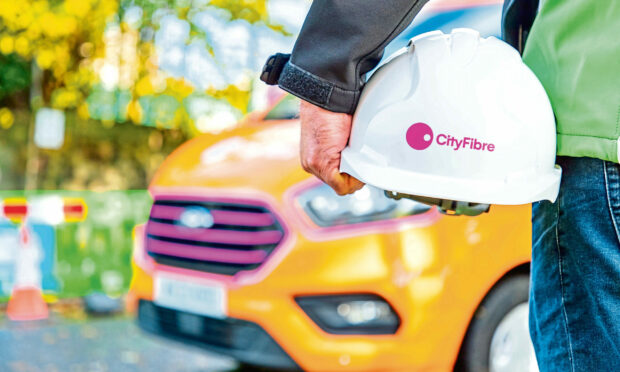 A CityFibre worker holding a hard hat with the firm's logo.
