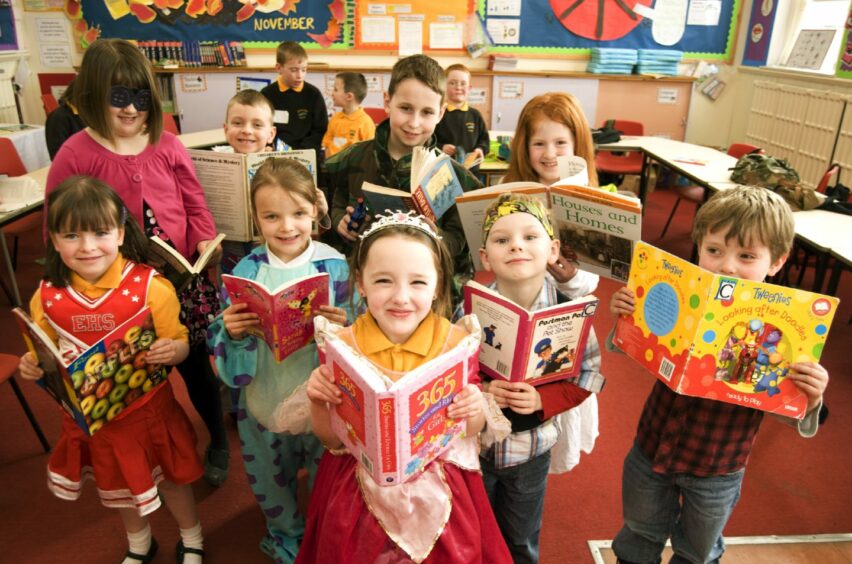 A group of children in costumes with books open in front of them for World Book Day