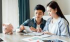 young Asian couple sits at a table planning their financial goals