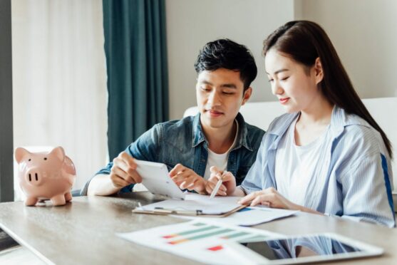 young Asian couple sits at a table planning their financial goals