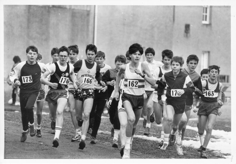 Teenage boys cross country running, the boy at the front of the pack is set to win