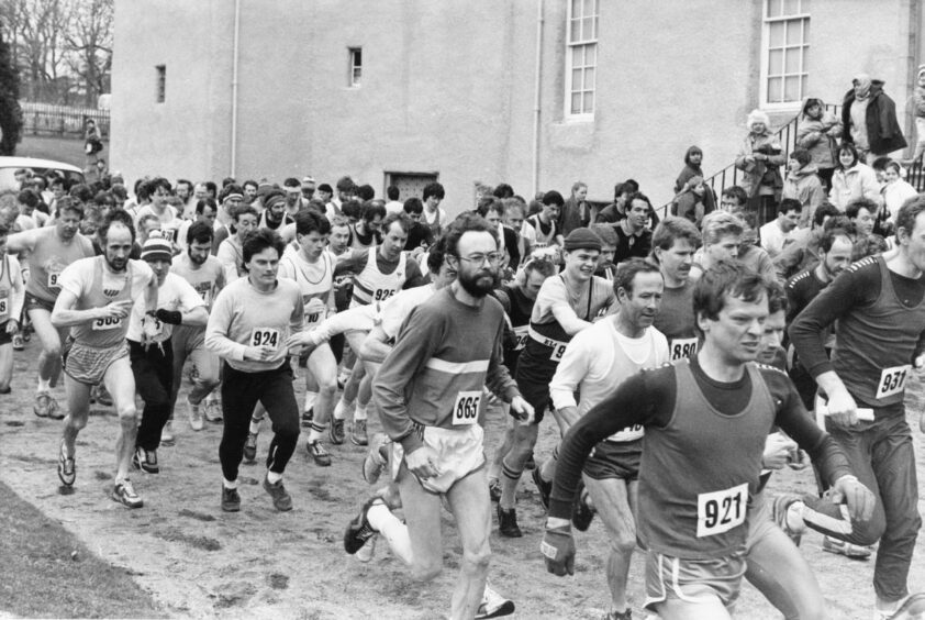 A crowd of men running past Drum Castle