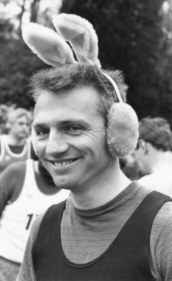 A young man with earmuffs with bunny ears attached smiling at the camera