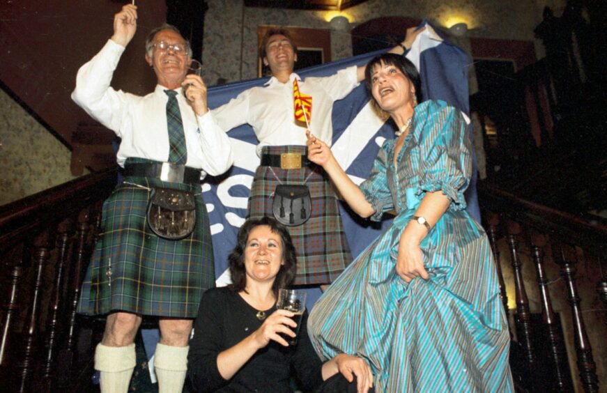 Allan Angus, left, celebrating the establishment of the Scottish Parliament in 1997. Also celebrating are Alasdair Allan, Iona Matheson and Ishbel Shand. Image: DC Thomson.