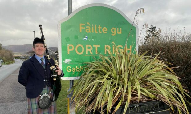 Alan Mackenzie, Pipe Major of the Isle of Skye Pipe Band standing by a road sign in Portree