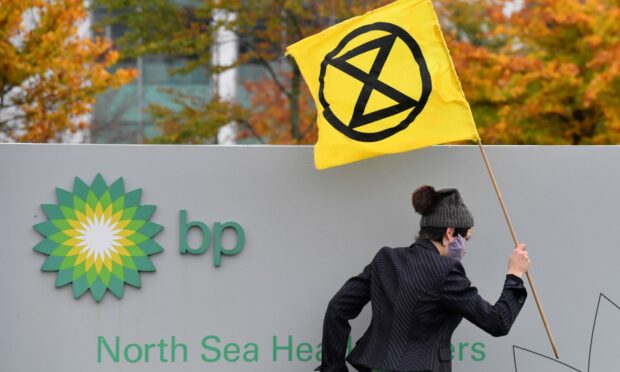 A protestor with Extinction Rebellion stages a protest at BP North Sea headquarters in Aberdeen in 2020