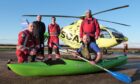 Men standing before a helicopter with one sitting in a kayak