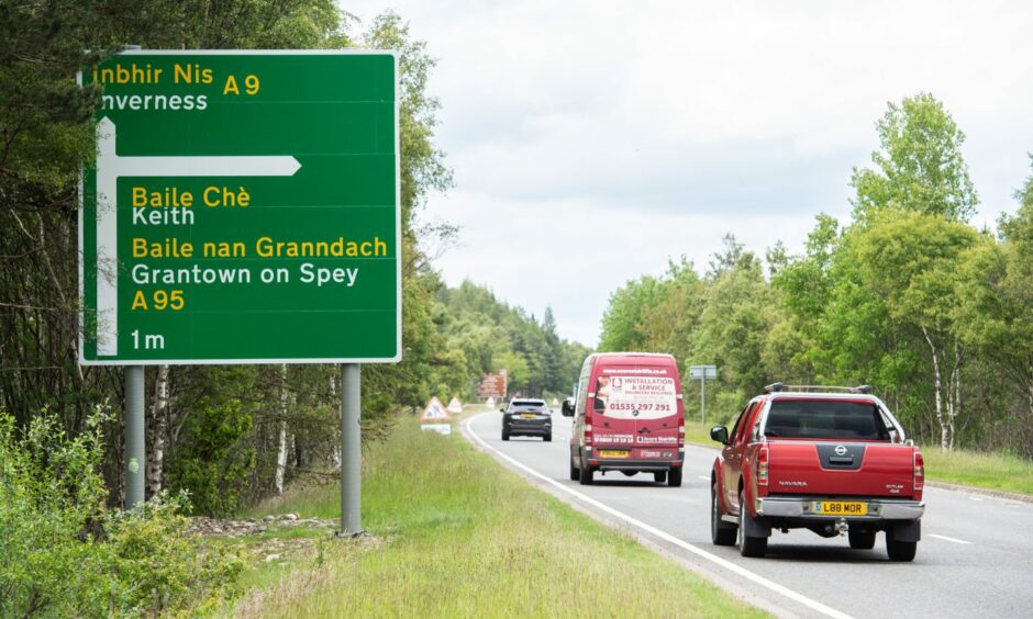 A green road sign pointing to Inverness with the turn off for Grantown on Spey.