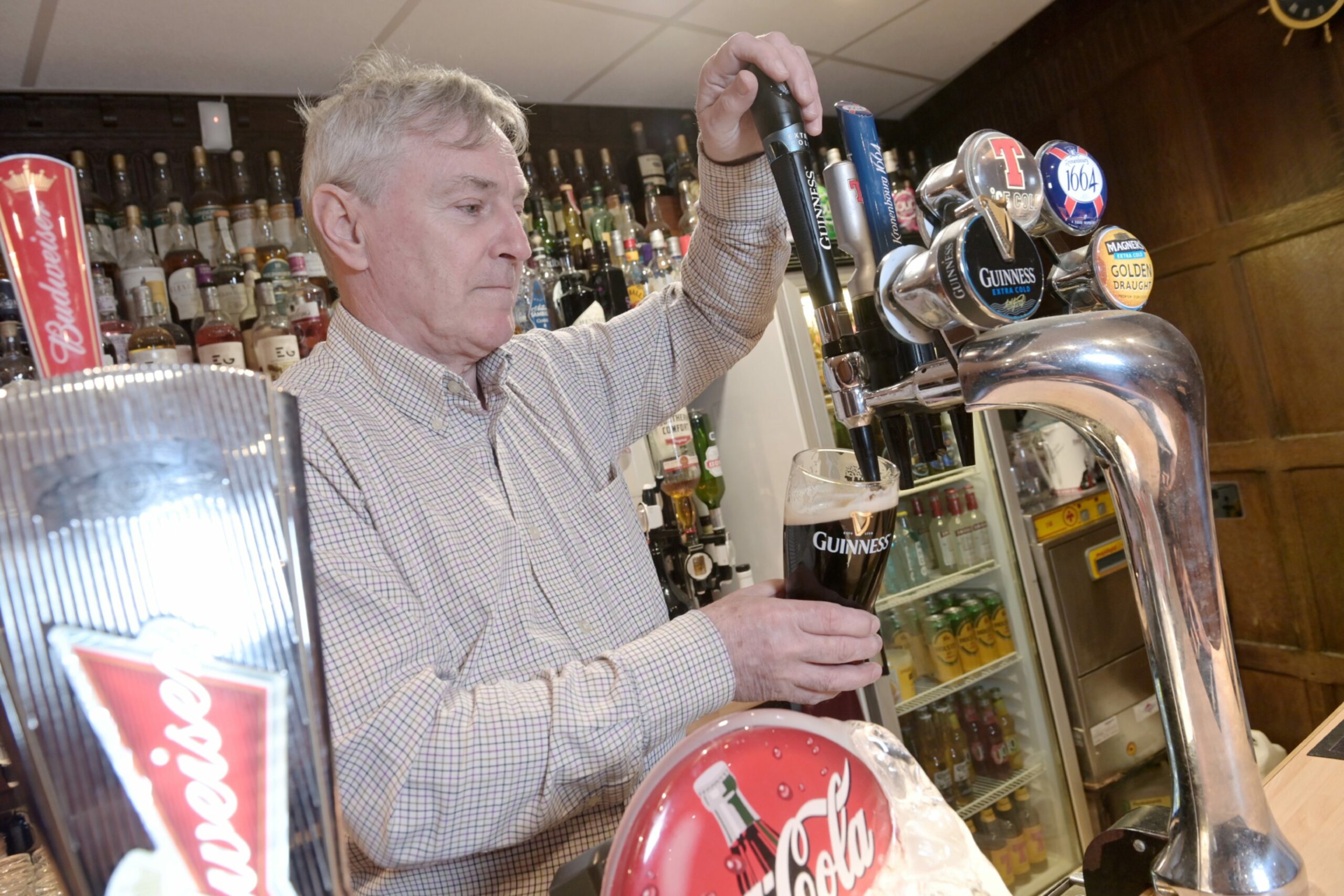 A member of staff at the Thistle Inn pouring a pint of Guinness in Inverness.