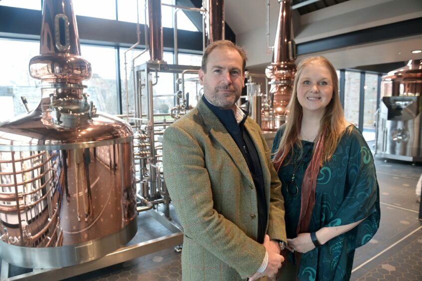 Jon and Victoria Erasmus in front of copper stills at the Uile-bheist distillery in Inverness