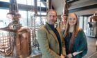 Victoria and Jon Erasmus in front of a copper still at the Uile-bheist distillery in Inverness.
