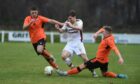 Ben Williamson, left, and Fraser Robertson, right, of Rothes try to put in a challenge on Forres' Connall Ewan