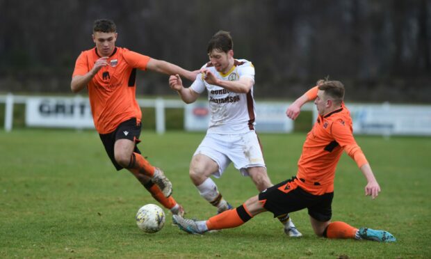 Ben Williamson, left, and Fraser Robertson, right, of Rothes try to put in a challenge on Forres' Connall Ewan