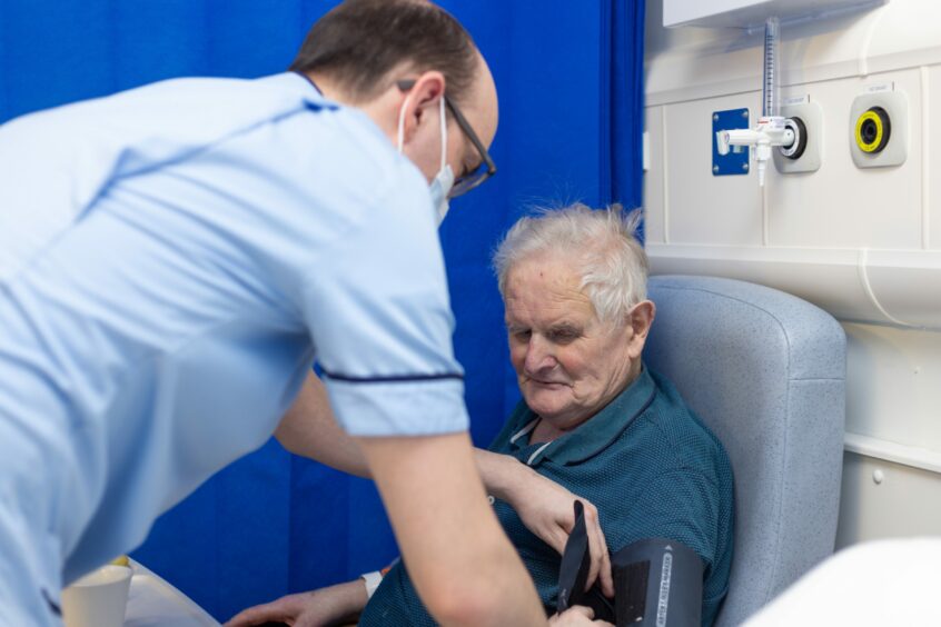 Lewis gives patient Harry Gray a check over on the ward. 