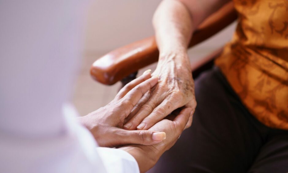 Stock image of carer holding elderly person's hand.