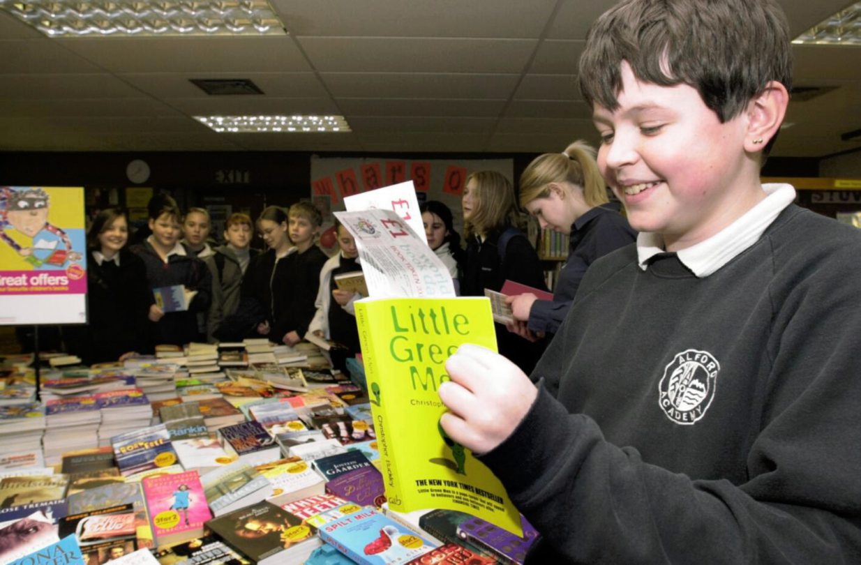 A boy using his world book day vouchers to buy a book at the school library