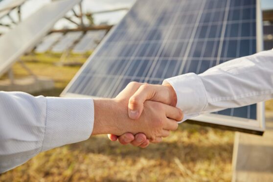 Business men shaking hands on a deal at a solar farm.