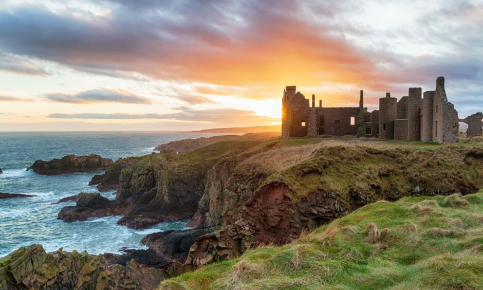 A dramatic landscape of Slains Castle in Aberdeenshire at sunset.