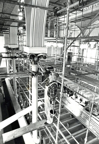 1980 - Painter Robert Vincent applies his brush to the scrollwork on one of the columns.