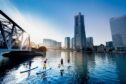 people on paddleboards head towards the Yokohama skyline