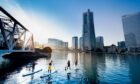 people on paddleboards head towards the Yokohama skyline