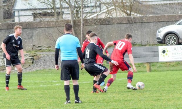 Inverness Athletic's two-goal star Ryan MacLeod holds off Thurso defence as he looks to pass to Sam Irving out wide in his team's 2-1 weekend win. Image: Courtesy of Inverness Athletic FC