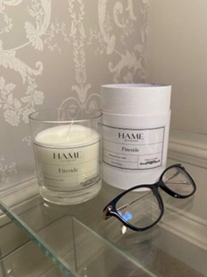 Candle by Hame interior next to glasses.