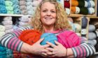 3 Bags Wool owner holding three thrum balls in her shop in Dufftown