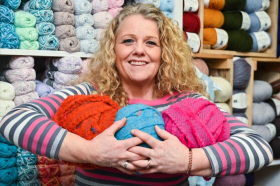 3 Bags Wool owner holding three thrum balls in her shop in Dufftown