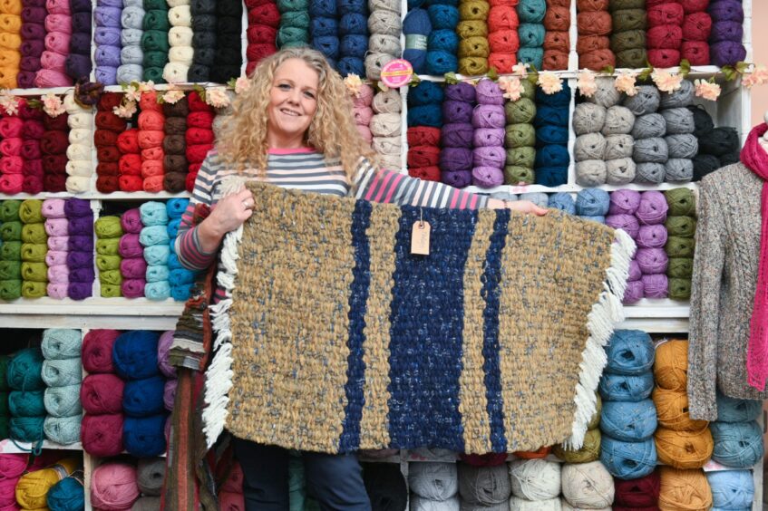 Sarah Fraser holding a rug made out of thrums in her store in Dufftown
