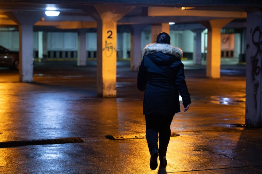 A woman walking at night in a secluded car park