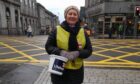 RNLI fundraising volunteer standing on the street in Aberdeen with a donations bucket in her hand
