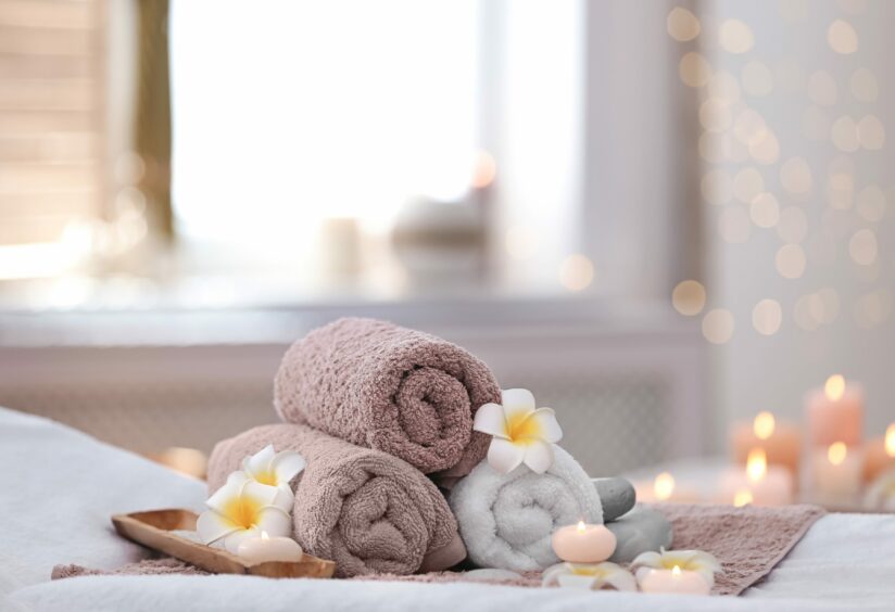 towels, candles and flowers on a bed