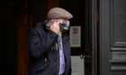 Gordon Macleod hides his face while leaving Aberdeen Sheriff Court. Image: DC Thomson