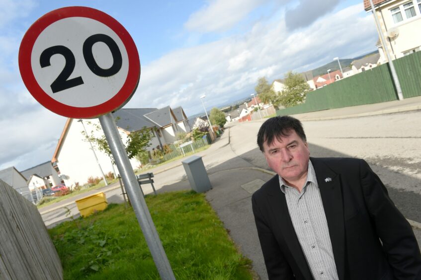 Councillor Ken Gowans, chairman of the council’s economy and infrastructure committee, standing next to a 20mph speed limit road sign.