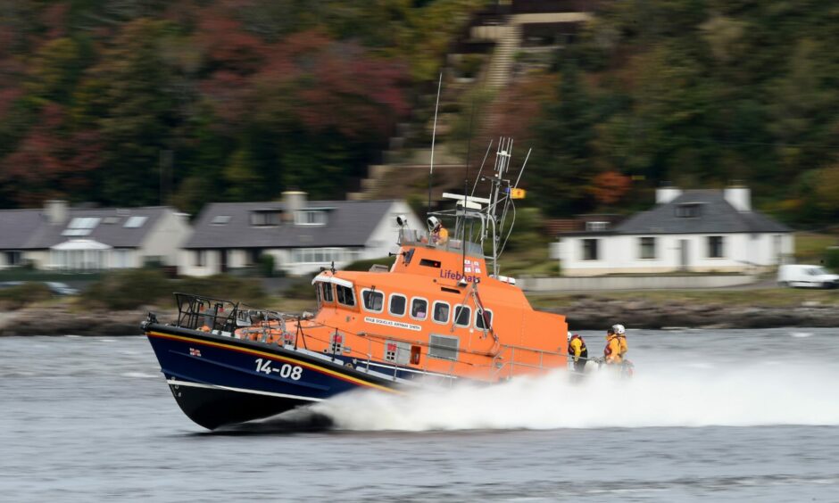 A picture of the blue and orange RNLI lifeboat from North Kessock splashing through the waves in the Moray Firth or Beauly Firth.