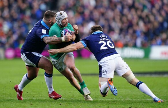 Man of the match Mack Hansen is tackled by Scotland's Hamish Watson.