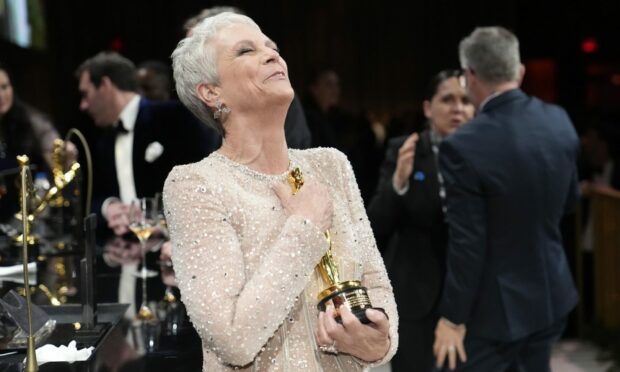 Jamie Lee Curtis clutches her Oscar for best performance by an actress in a supporting role after it is engraved at the Governor's Ball. Image: AP Photo/John Locher.