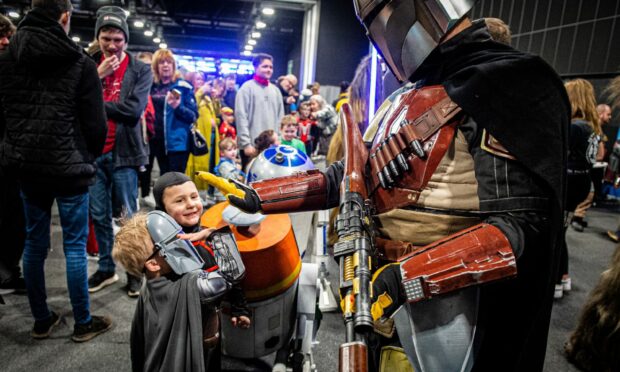 A young Mandalorian fan high fives one of the Mandalorian characters. Image: Wullie Marr / DC Thomson