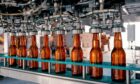 Row of bottles under machine in factory