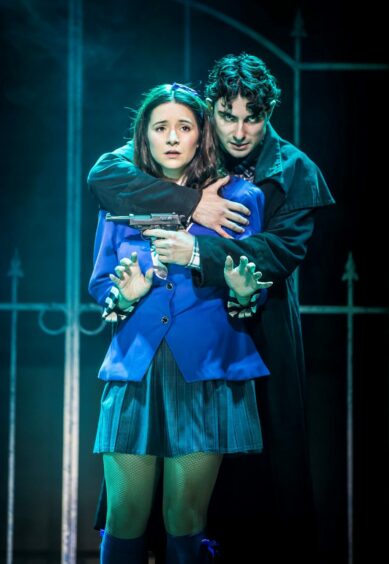 Jenna Innes onstage as Veronica in a tense embrace with character JD while performing Heathers The Musical.